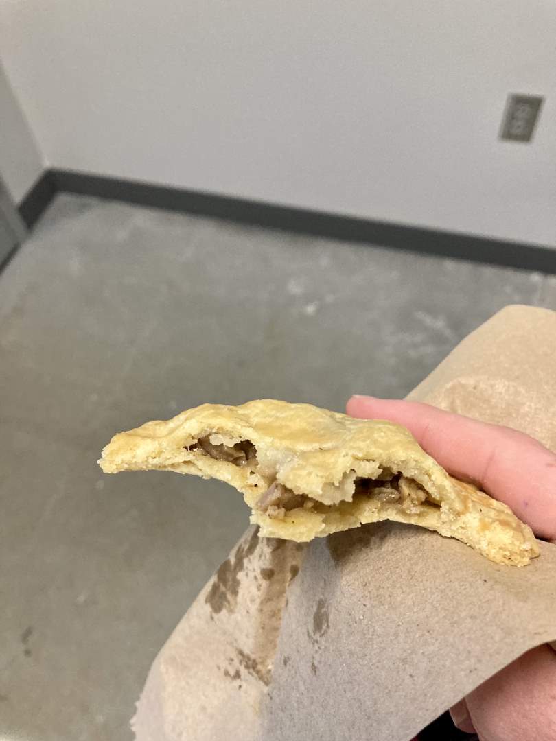 a hand holding a half-eaten pork pie