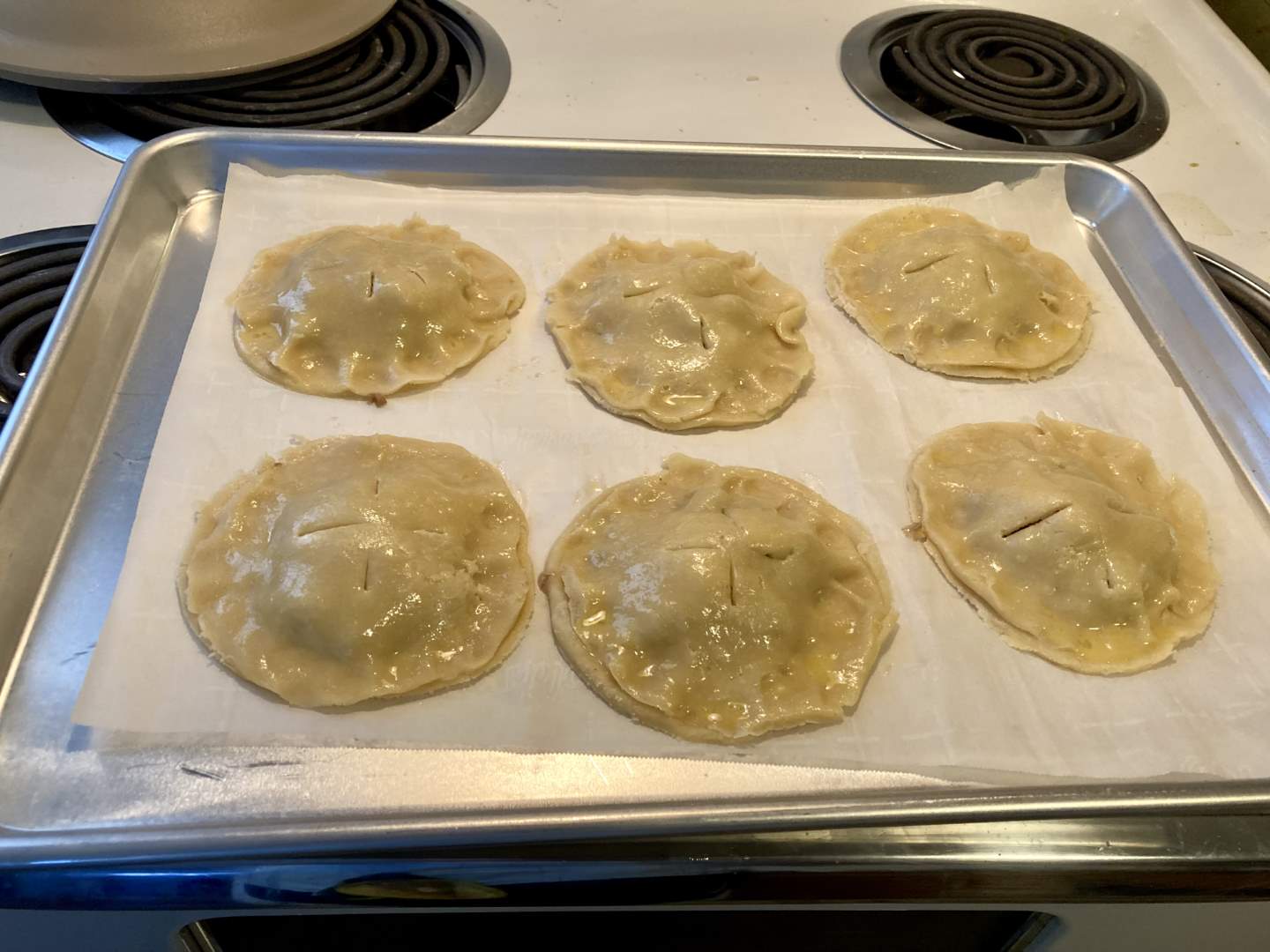 the pork pies uncooked on the baking sheet